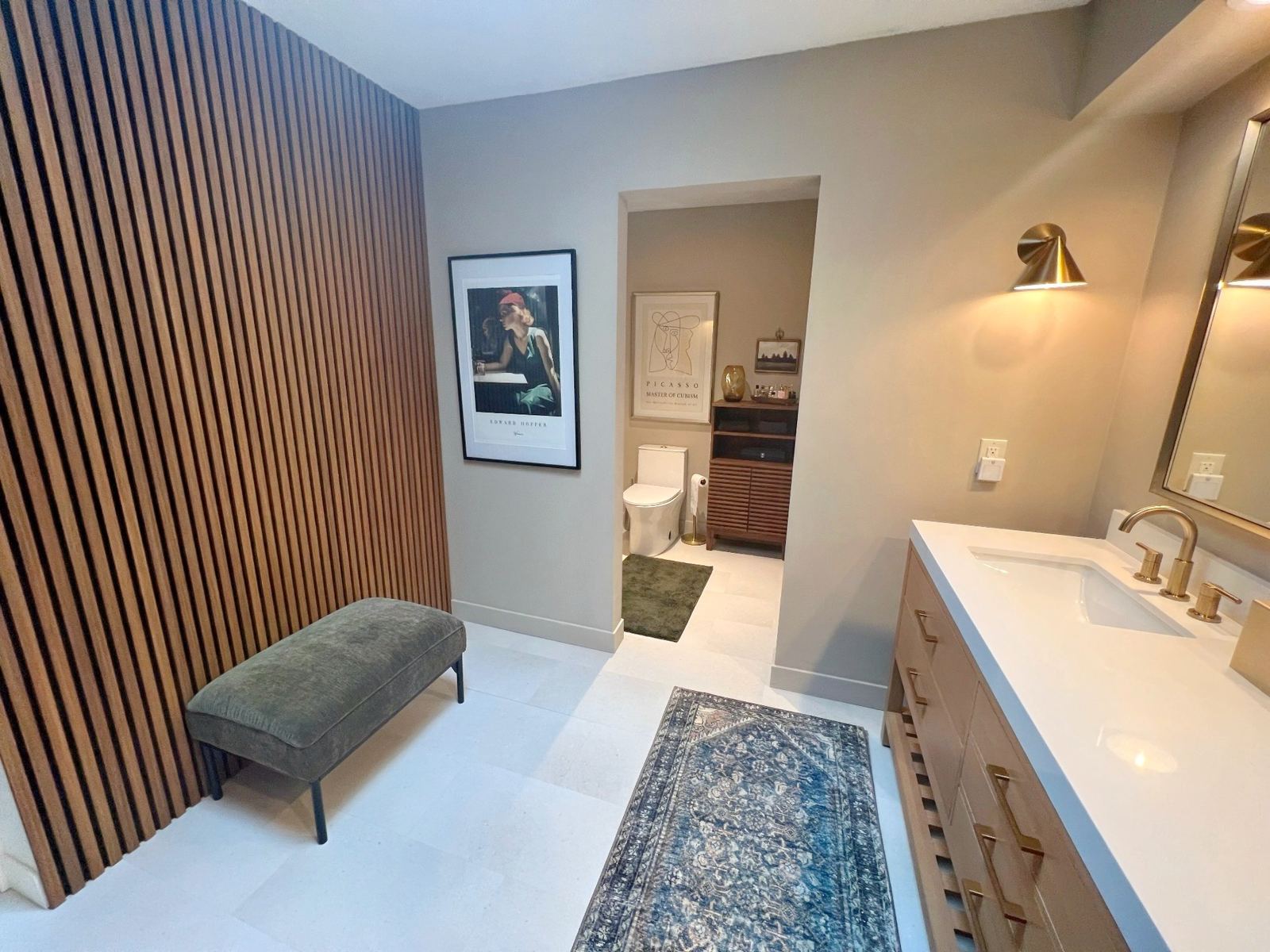 Bathroom with vertical wood slat wall, brass fixtures, and framed art