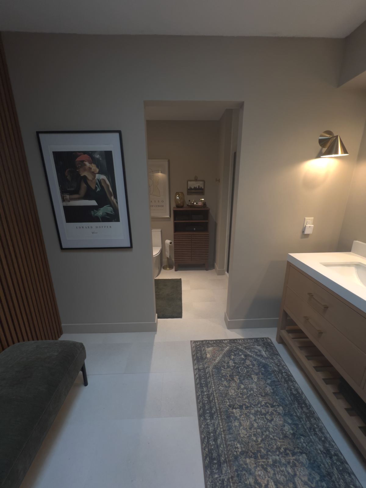 Primary bath niche with art, brass sconce, and teak bench seating