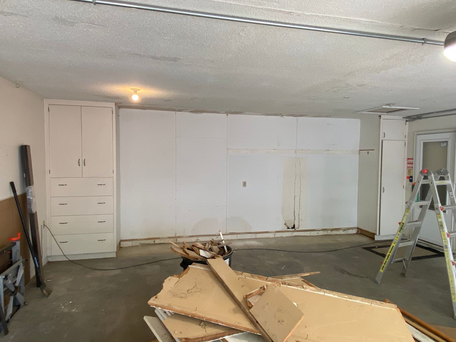 Empty garage during demolition with exposed drywall and debris