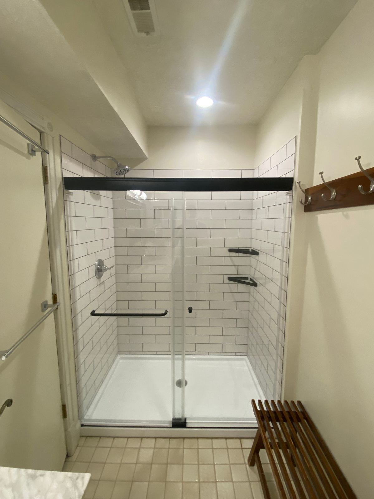 New white subway tile shower with matte black hardware and glass doors