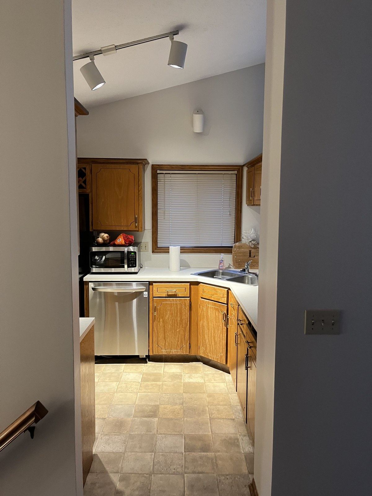 Original galley kitchen with oak cabinets, laminate counters, and tile-look vinyl floor before renovation