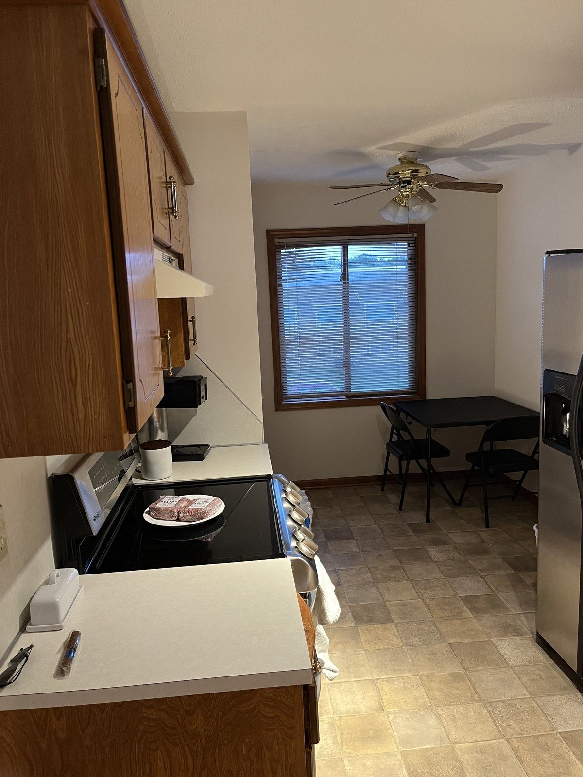 Original kitchen range wall with oak cabinets, laminate counters, and vinyl tile floor before renovation