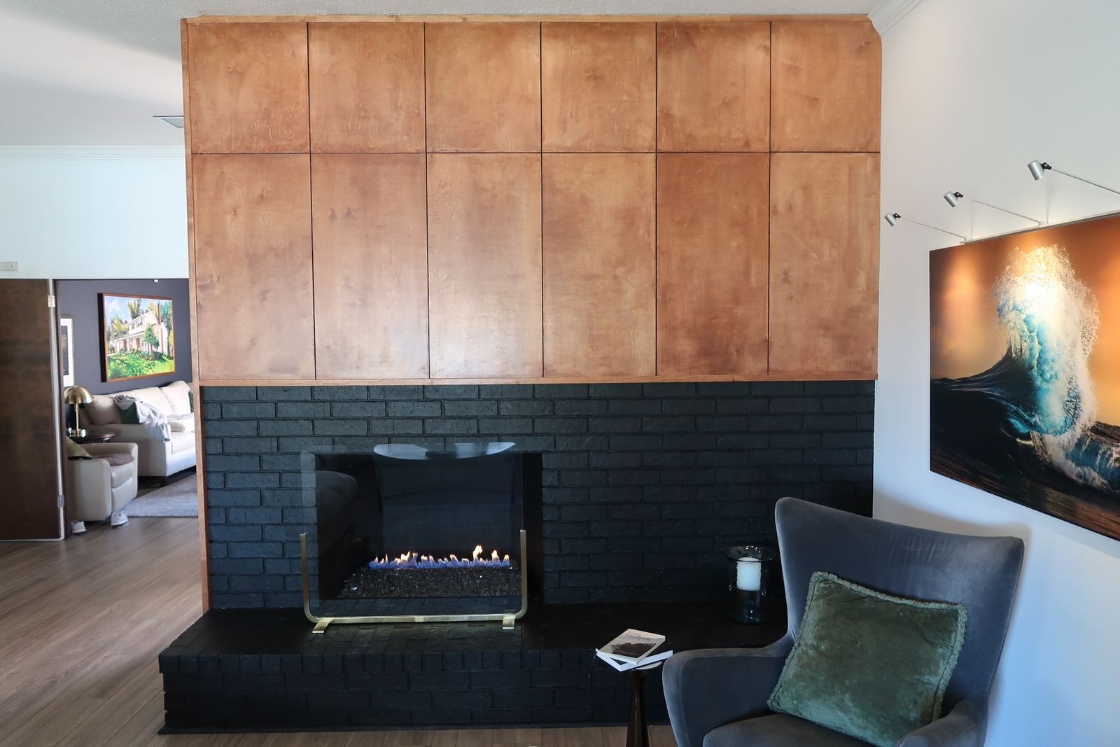 Living room with custom wood-paneled fireplace surround and painted black brick